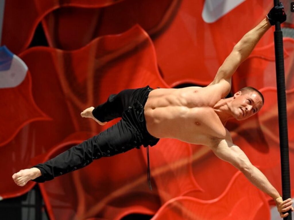 Circassien réalisant la figure du drapeau sur un mât chinois, corps parfaitement aligné à l’horizontale