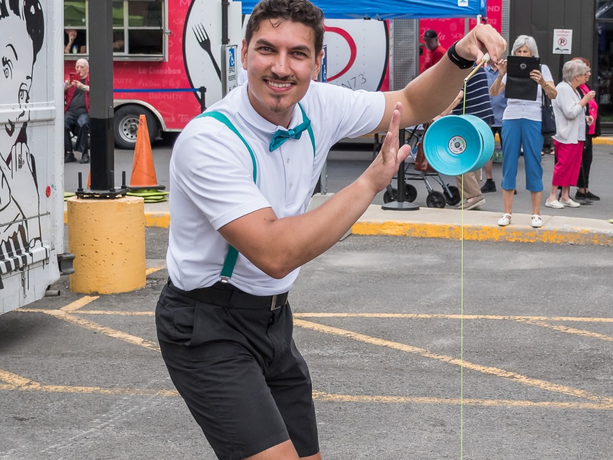 Diaboliste souriant à la caméra, son diabolo suspendu à la verticale dans la corde devant lui