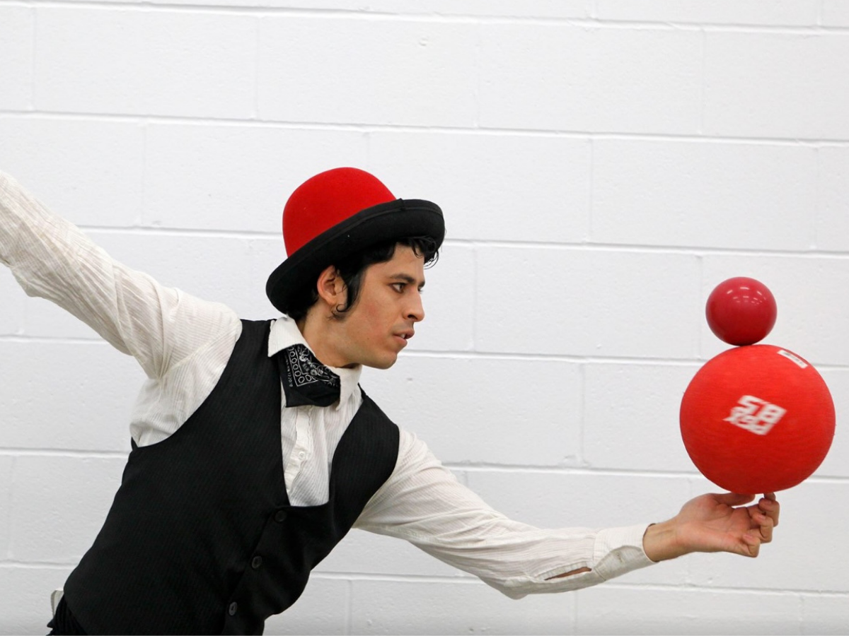 Un amuseur tenant deux ballons en équilibre sur le bout de son doigt.