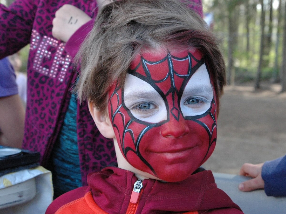 Enfant avec le visage entièrement maquillé en Spiderman, dans les couleurs rouges et noires du superhéros