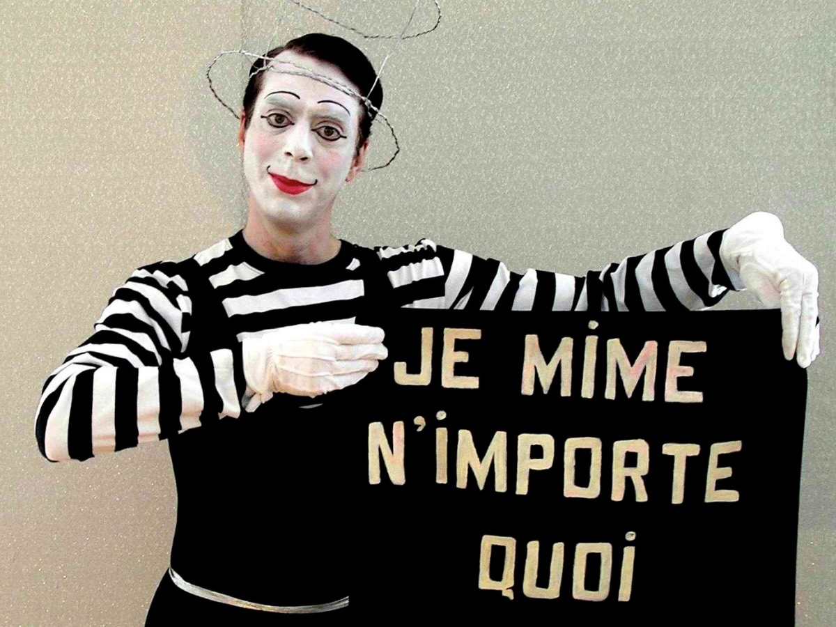 Mime expressif brandissant une affiche écrite « Je mime n’importe quoi, demandez » en pleine animation