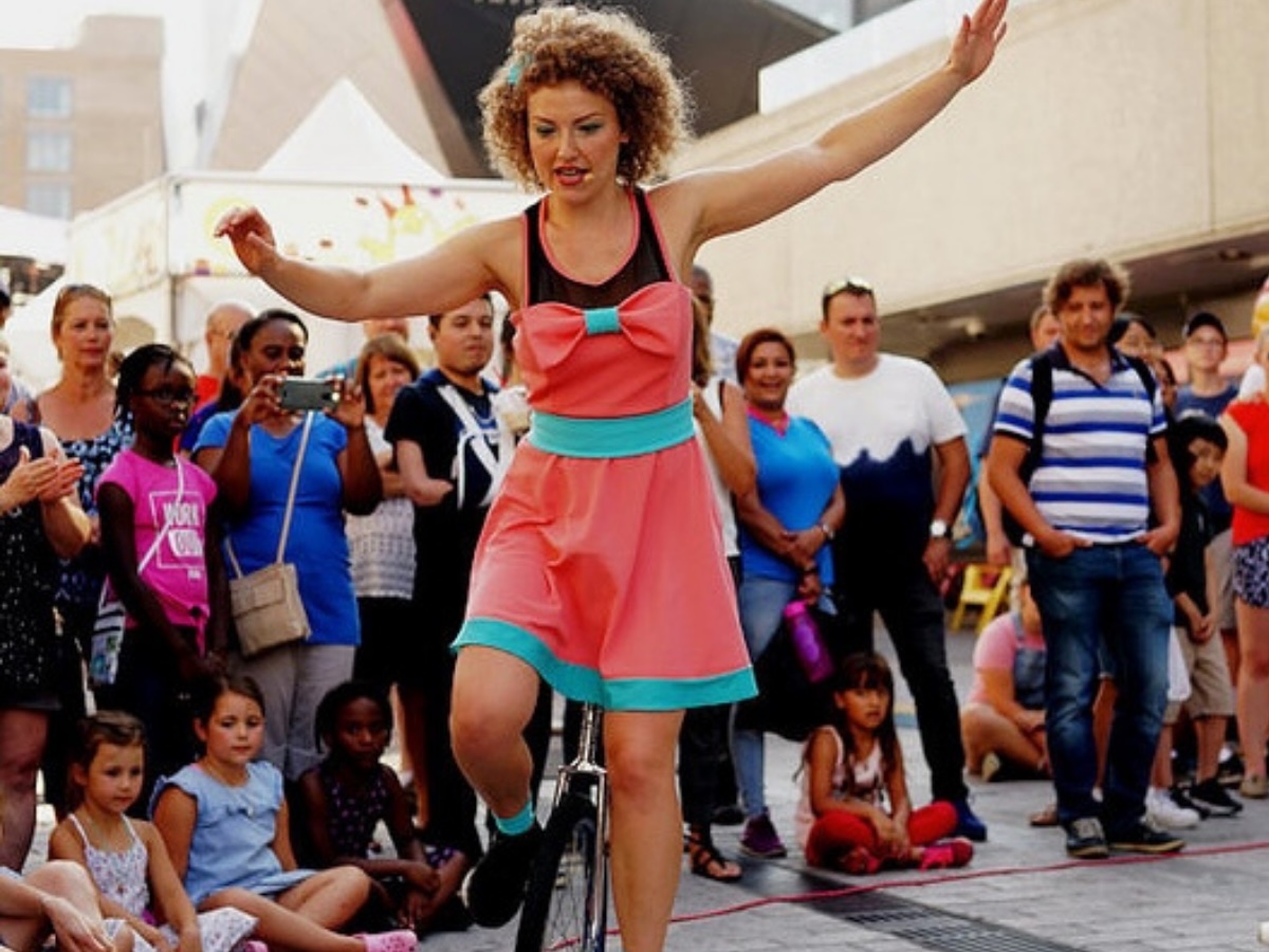 Monocycliste féminine au centre d’une foule formant un cercle, en action lors d’une animation