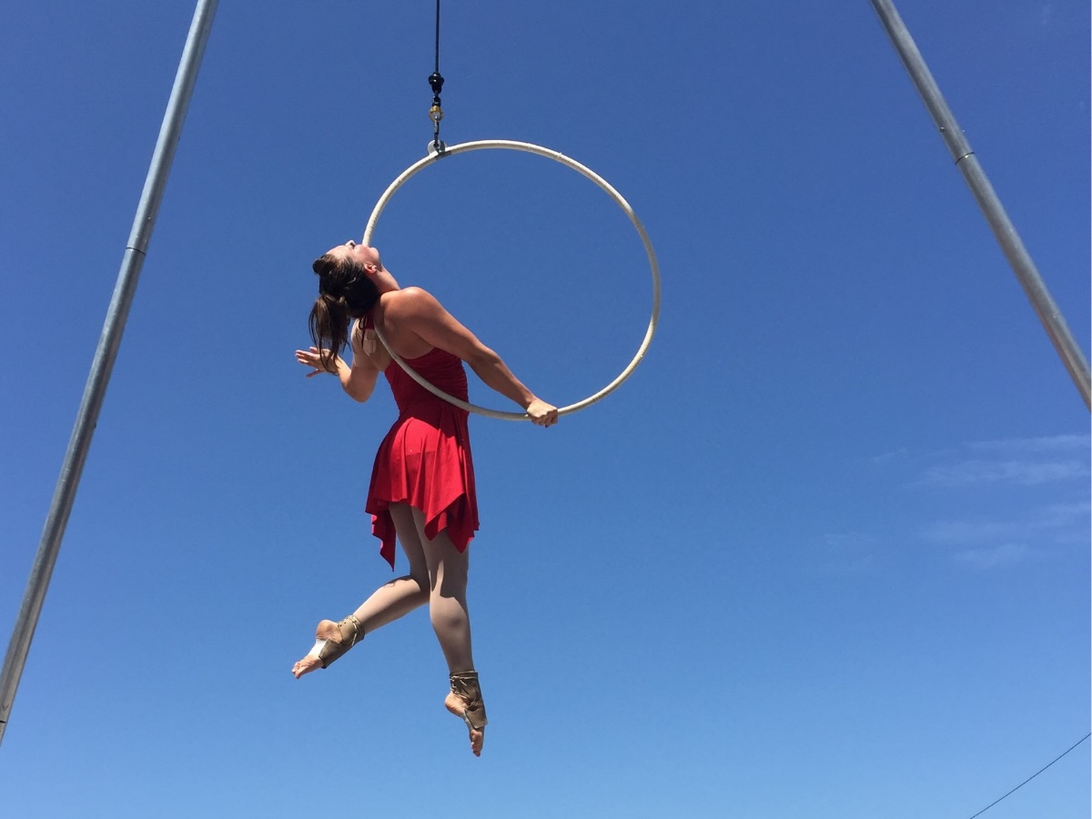 Artiste aérienne exécutant une figure suspendue par le dos et un bras sur cerceau aérien
