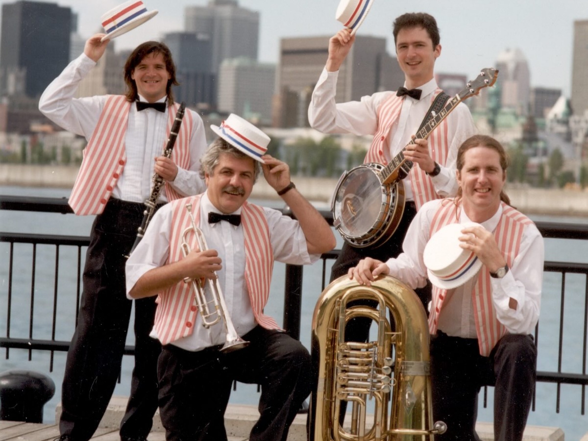 Musiciens en quatuor avec débardeurs rayés colorés, instruments variés en main lors d’une animation publique
