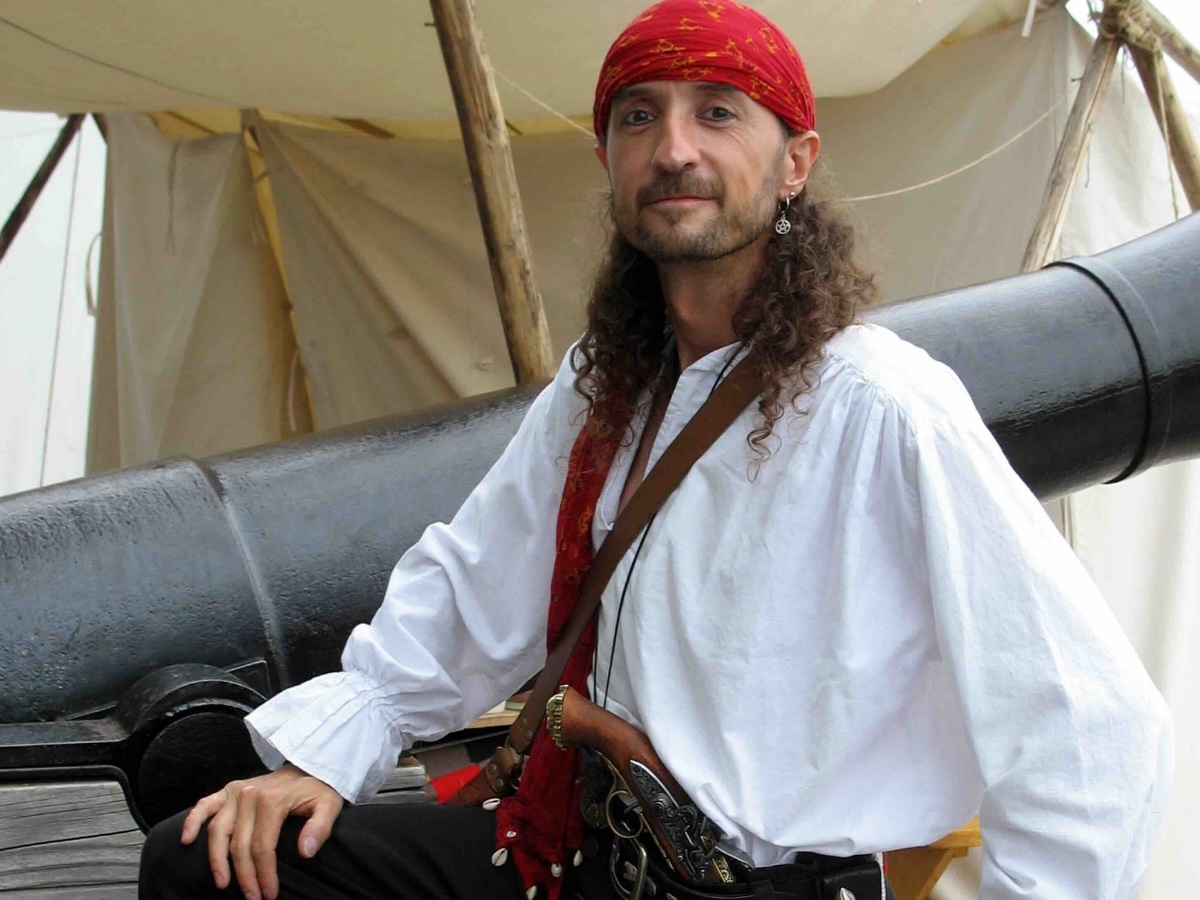 Personnage costumé en pirate se tenant fièrement devant un canon décoratif pour une animation