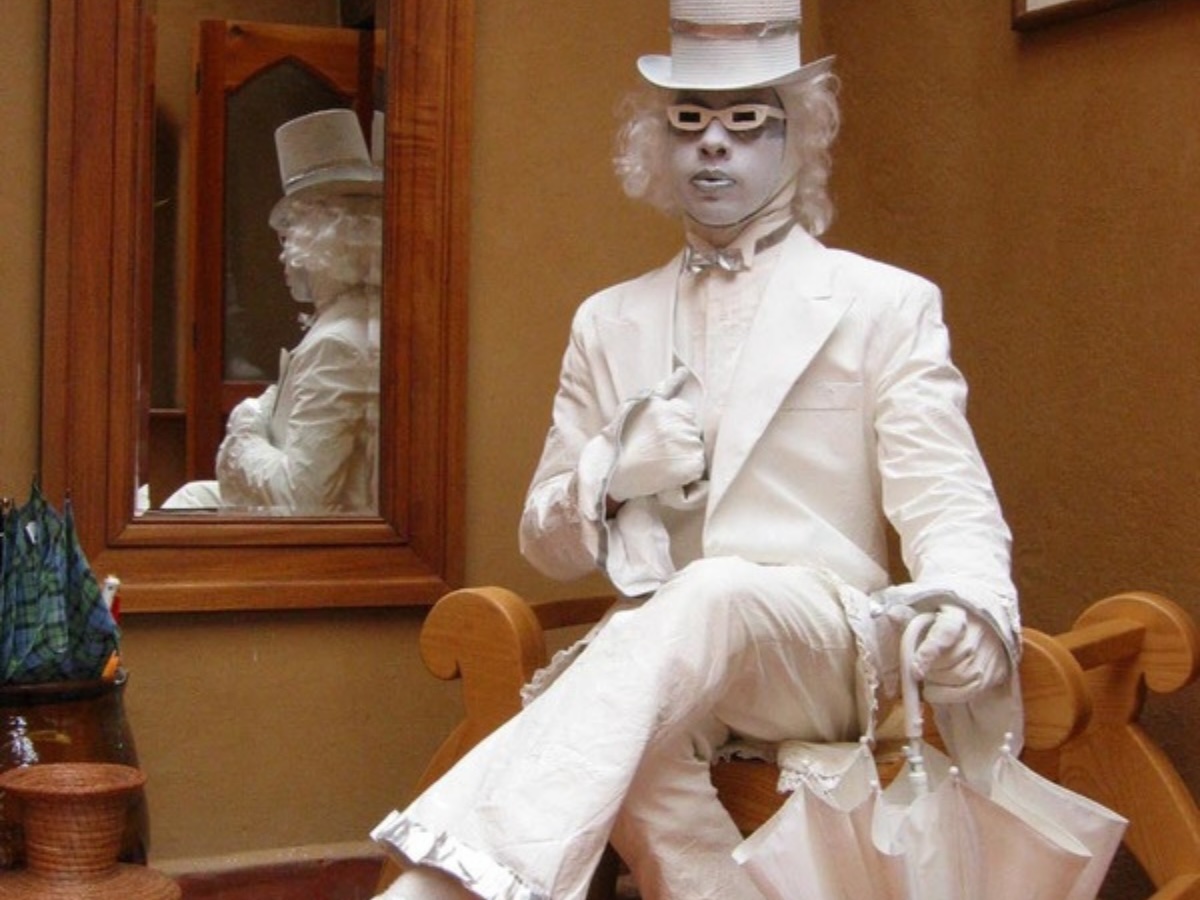 Statue vivante toute vêtue de blanc, immobile et assise sur un banc faisant des animations au Québec